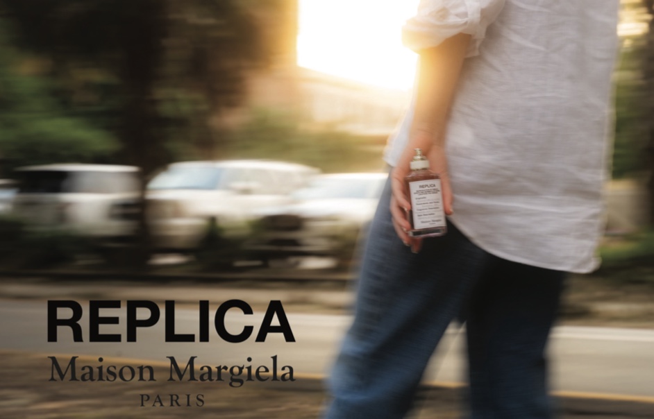 Final campaign — golden-hour motion, REPLICA bottle in hand, the Maison Margiela REPLICA lockup set against blurred passing cars