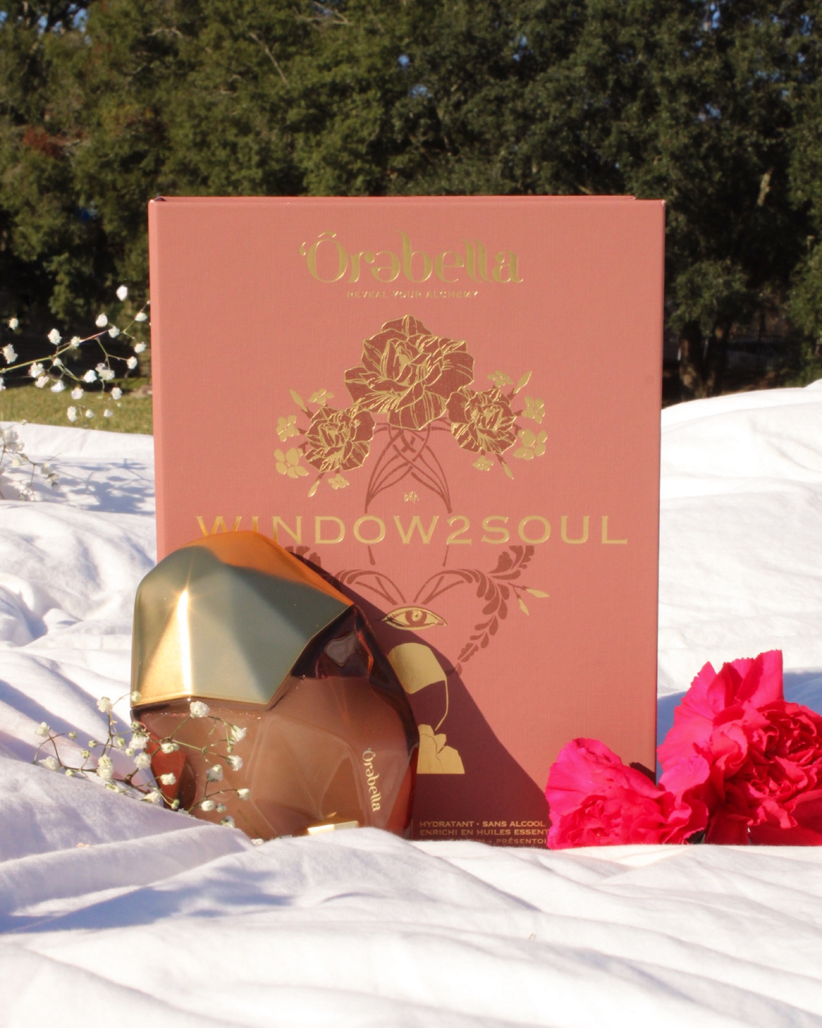 Window2Soul — the rose-gold bottle, its illustrated outer box, paired with red carnations and baby's breath