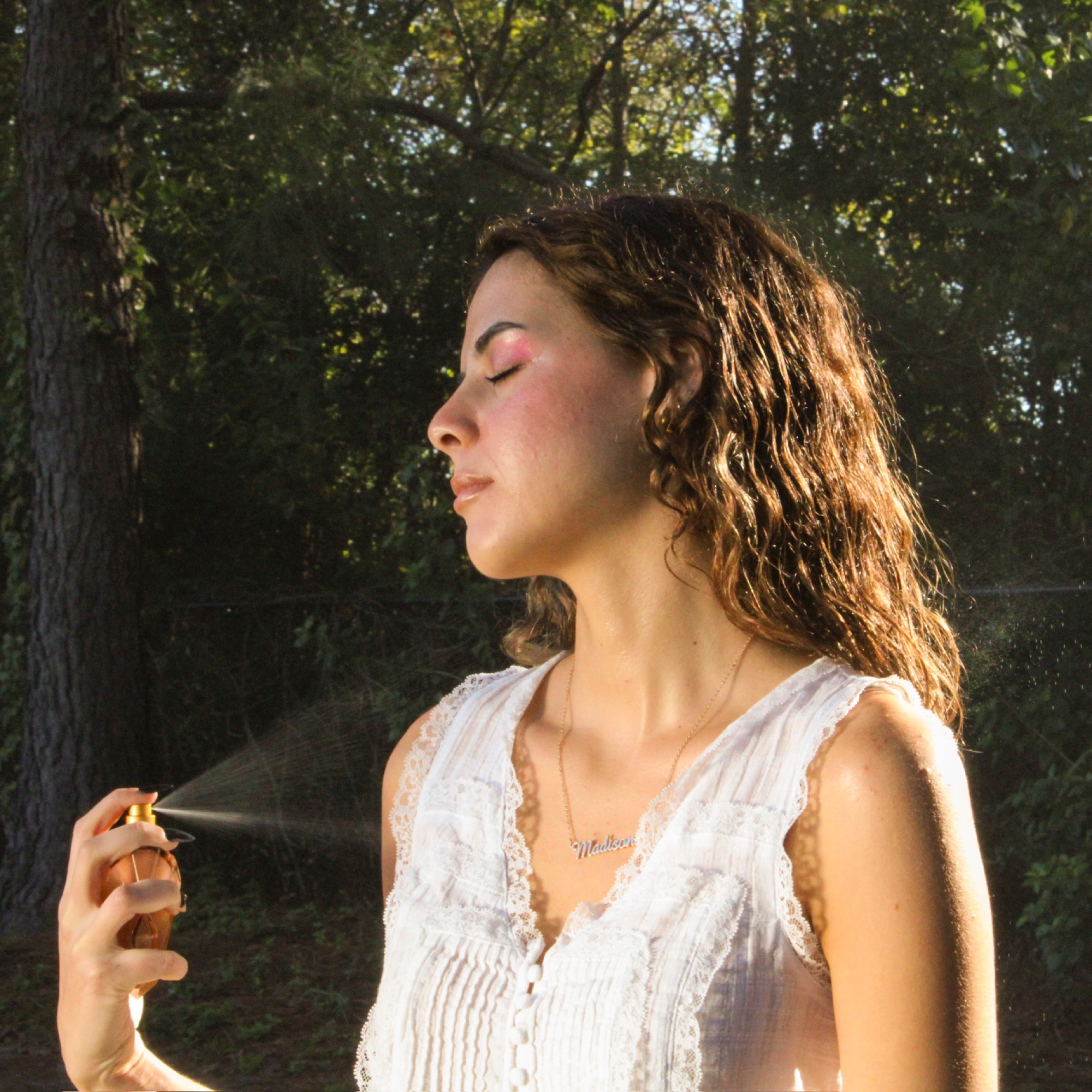 Window2Soul editorial — sun-lit closeup of the model spraying the parfum, eyes closed in the forest